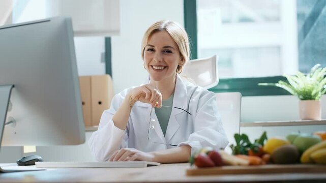 Video of beautiful smart nutritionist woman working with computer while looking at camera in the nutritionist consultation