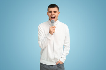 Young man singing with microphone on blue background