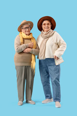Senior female friends in stylish clothes on blue background