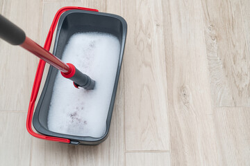 Mop in bucket of soapy water with floor cleaning liquid, copy space.