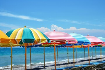 Vibrant row of striped beach umbrellas against a clear blue sky by the ocean