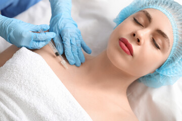 Beautiful young woman receiving filler injection in beauty salon