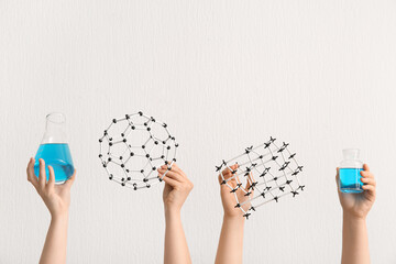 Female hands holding filled flask with bottle and molecular models on white background. Chemistry...