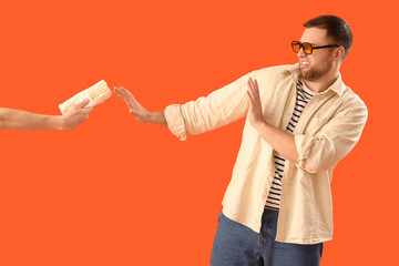 Young man refusing hand with doner kebab on orange background
