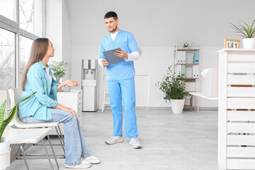 Male receptionist with waiting patient in clinic