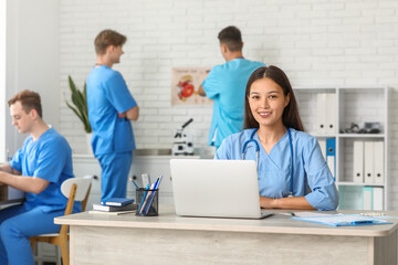 Obraz premium Female Asian doctor working with laptop at table in clinic