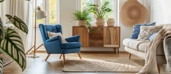 Wooden cabinet near a blue chair in a comfortable living room with a beige sofa