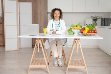 Mature female nutritionist sitting at table in kitchen