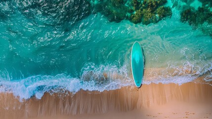 Fototapeta premium Aerial View of a Pristine Beach with a Blue Surfboard on the Shore