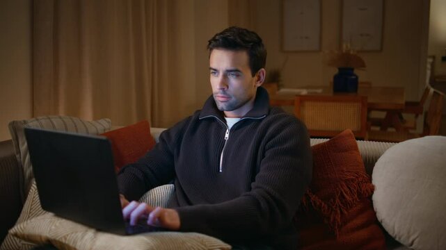Serious freelancer working dark home on sofa closeup. Smart programmer typing 