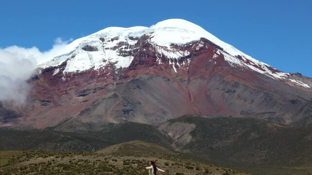 latina woman with arms outstretched facing Chimborazo volcano (6,263 m), Ecuador