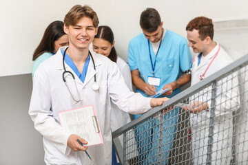 Male doctor with clipboard on stairs in clinic