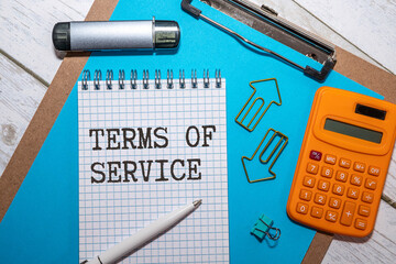 TERMS OF SERVICE text written on paper clipboard on laptop