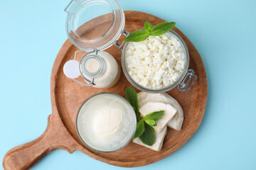 Different dairy products and mint on light blue background, top view