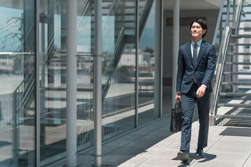 Obraz premium ビジネス街・オフィス街を歩くビジネスマン男性（飛び込み営業・外回り・営業マン・セールスマン） 