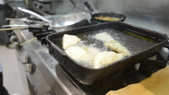 preparazione di panzerotti fritti in una pentola piena di olio nella cucina di un ristorante