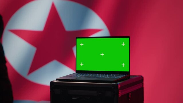 North Korea secret police agent uses mass propaganda tools on green screen laptop to influence population minds. Pyongyang regime commits PsyOp sabotage using mockup device, camera A