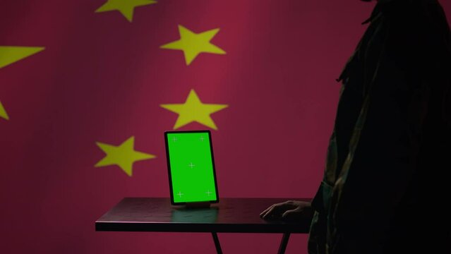 Chinese engineer uses green screen tablet to make fake accounts on social media promoting communist ideology. Technician doing cybersecurity job for CCP government with mockup device, camera B