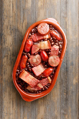 brazilian feijoada in ceramic bowl isolated on rustic wooden background. Copy space