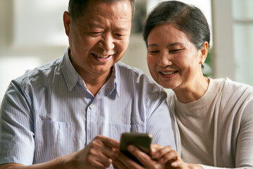 senior asian couple using cellphone together at home