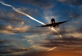Landing airplane at colorful sunrise with beams of sun lights. Concept of transport, weather, travel and happy vacation