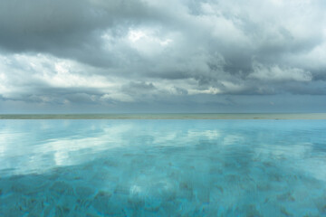 Fototapeta premium Seaside swimming pool with clouds in the sky and reflections on the water in the morning