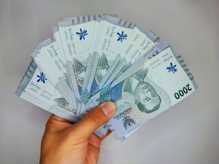 Indonesian money worth 2000 rupiah in his hand