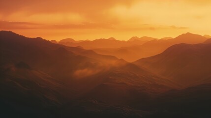 Naklejka premium Beautiful sunset over mountains with warm orange and yellow tones, creating a serene and picturesque landscape view.