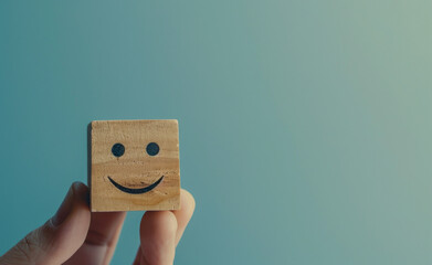 A hand holds a wooden block with a smiley face symbol representing positive customer service
