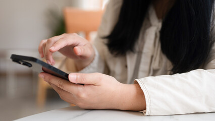 Close up hand of woman using smartphone at coffee shop cafe