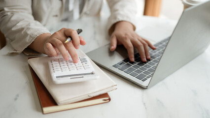 Close-up of hands using a calculator and notebook