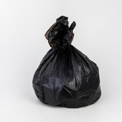 Black trash bag against a white background shot inside a studio.