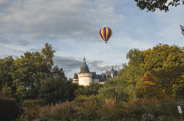 A colorful balloon soars above a french chateau
