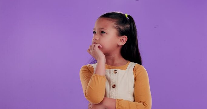 Confused, child and hand with thinking in studio for question, doubt and wonder in decision. Uncertain, little girl and gesture with contemplating for idea, planning and solution on purple background