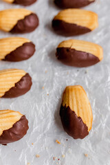 Chocolate-dipped madeleine cookies on parchment