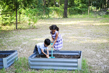 Two children gardening in raised garden beds outdoors