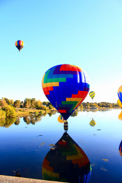 Dawn ascent of vibrant balloons over water