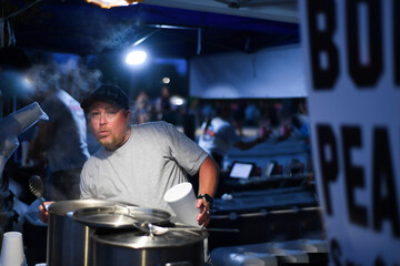 Vendor at a night market serving hot boiled peanuts with a surpr