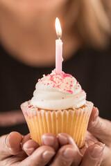 Close up of a lit birthday candle with a lady in the background