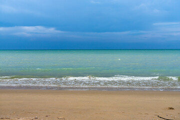 Fluffy clouds drift across a bright summer sky above a tropical beach with turquoise waves lapping at the shore