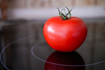 Red tomato on a black ceramic hob in the kitchen