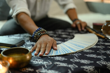Fortune teller arranging tarot cards on desk lit candles and antique items. Astrologists, forecasting and divination concept