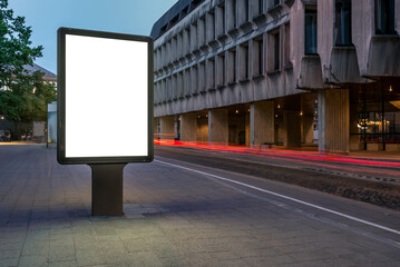Street Billboard Mockup On Sidewalk At Night. Outdoor Advertising Lightbox with Car Light Trails In The Background