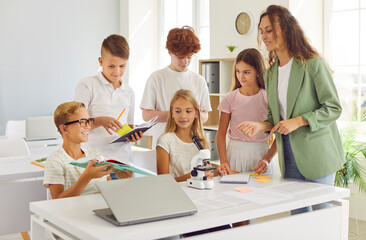 Dedicated teacher engages in a group check of students notebooks at school classroom. Together with pupils, she fosters teamwork and a shared commitment to excellence during the lesson.
