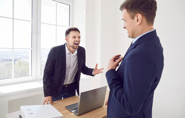 Irritated businessman in the office shouts at a man, close-up. Concept of shouting in the work, dissatisfaction with an employee. Negative emotions in the workplace, pressure on a colleague