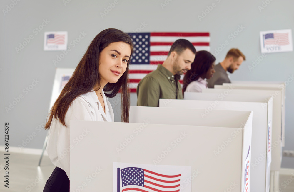 Sticker American woman votes at polling station during democratic presidential elections. Portrait of beautiful young lady standing in booth with USA flag and with other people marking ballots in background