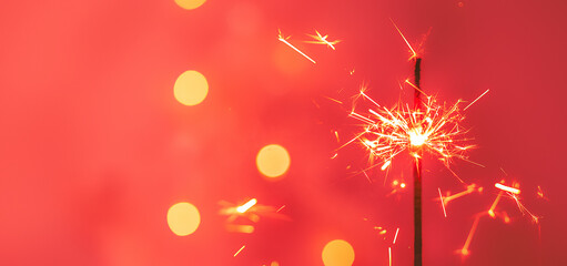 Beautiful sparklers from sparklers on a red background of New Year's bokeh, Christmas mood,...