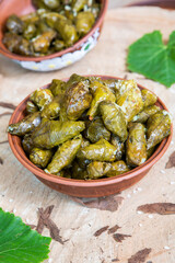 Dolma a stuffed grape leaves in a clay bowl on wooden background