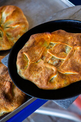 
Romanian traditional pie with cheese cooked on a pan on the fire outside. Food from Romania and Republic of Moldova.
