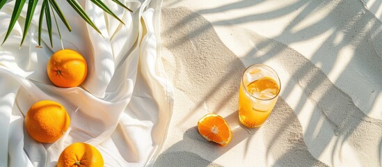 Fresh Oranges, Cocktail, and Tablecloth on White Sand with Tropical Vibe